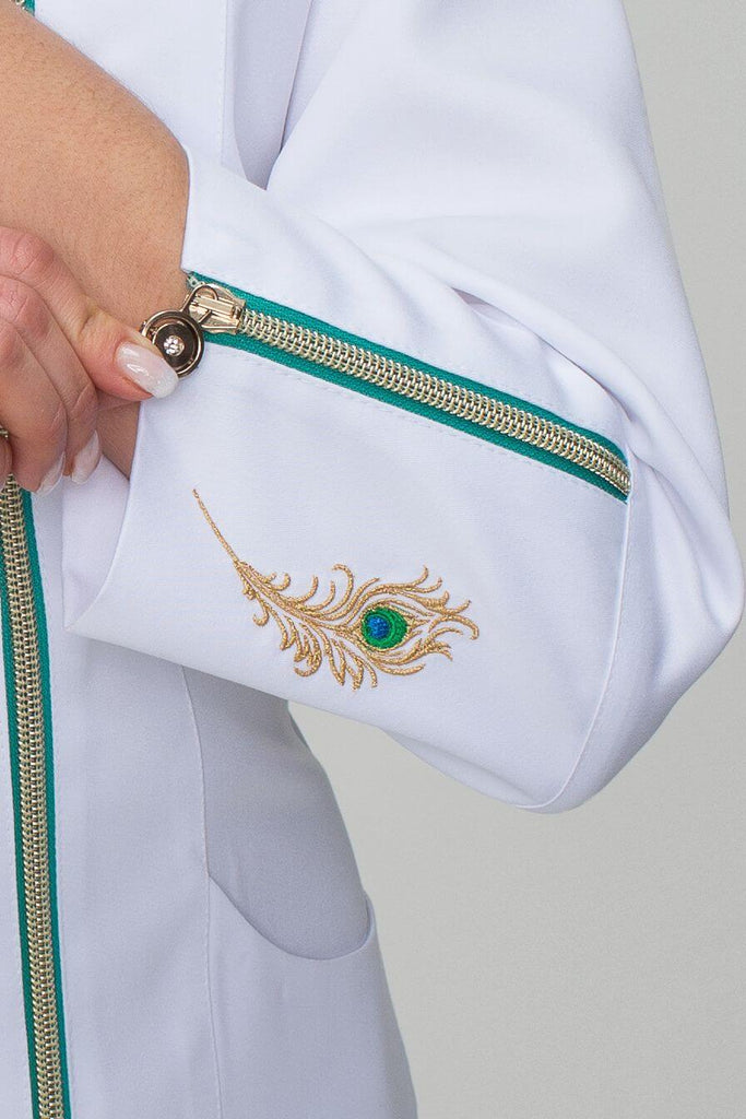 Detail výšivky páva na rukávu bílé dámské zdravotnické halenky od zdravotnického oblečení Medireina. 